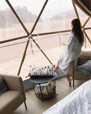 a woman sitting on a chair in front of a window at BUBBLES LUXURY CAMp in Wadi Rum