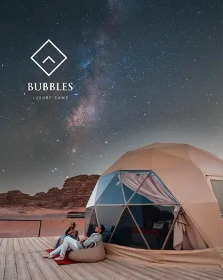 two people sitting in front of a tent under the stars at BUBBLES LUXURY CAMp in Wadi Rum