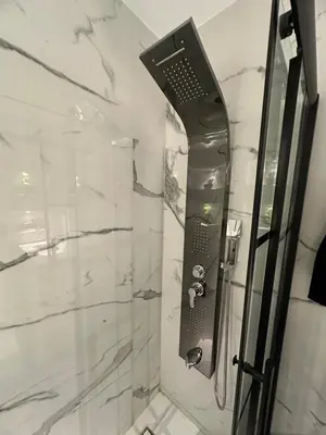 a shower in a bathroom with a glass shower backdoor at Cozy Modern Apartment Damac Abdali in Amman