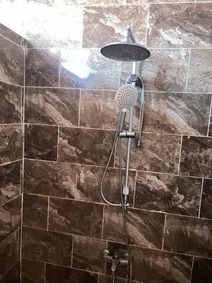 a shower in a bathroom with brown tiles at Wadi Rum Bedoun in Wadi Rum