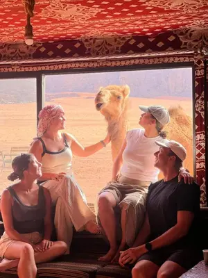 a group of people sitting in front of a camel at Wadi Rum Bedoun in Wadi Rum