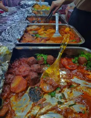 a buffet line of trays of food with utensils at Oasis of Civilizations Camp in Wadi Rum