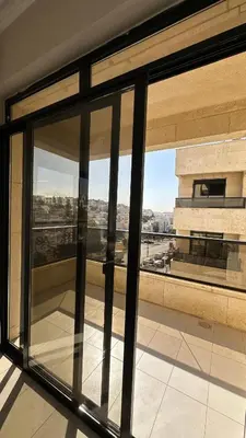 a view through a glass window of a building at Modern 2BR Apartment in Deir Ghbar in Amman