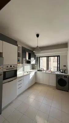 a large kitchen with white cabinets and appliances at Modern 2BR Apartment in Deir Ghbar in Amman