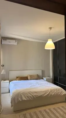 a bedroom with a white bed and a lamp at Modern 2BR Apartment in Deir Ghbar in Amman