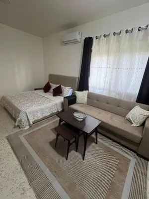 a living room with a couch and a bed and a table at Cozy Studio Apartment in Amman