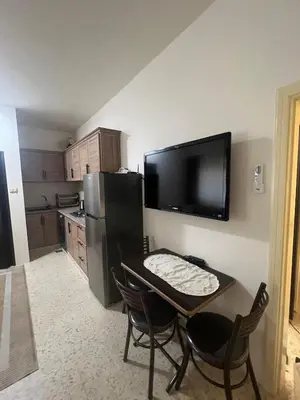 a small kitchen with a table and a television on the wall at Cozy Studio Apartment in Amman