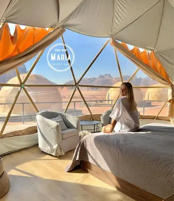 a woman sitting on a bed in a tent at MARIA LUXURY CAMp&BUBBLES ROOM in Wadi Rum