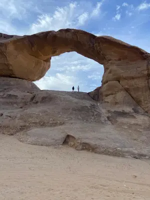 two people standing under an arch in a rock formation at Stars light tent wadi rum in Wadi Rum