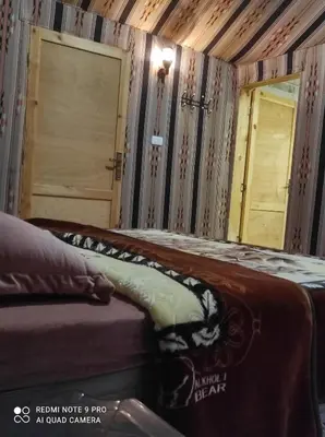 a bedroom with a bed and a mirror and a door at Oasis of Wonders Camp in Wadi Rum