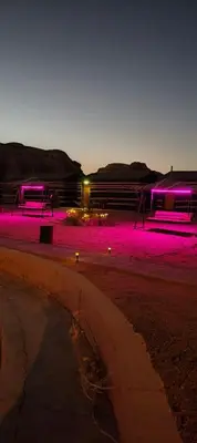 two picnic tables with purple lights in a park at Rotana camp in Disah