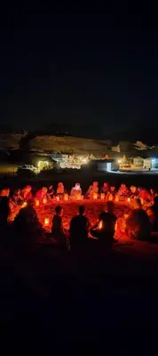 a group of people sitting on the beach at night at Rotana camp in Disah