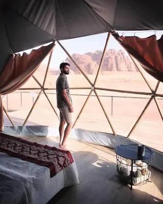 a man standing in a tent with a view of the desert at Magic rum luxury camp in Wadi Rum