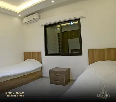 a small bedroom with two beds and a window at Farm Luxury in Shūnat Nimrīn