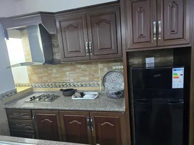 a kitchen with wooden cabinets and a black refrigerator at Studio 3 Cozy Amman Central Near Rainbow Street & First Circle in Amman