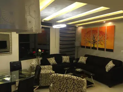 a living room with a black couch and a table at شقة مفروشة للإيجار بالرابية بالقرب من السفارة الصينية in Amman