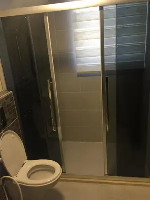 a bathroom with a toilet and a glass shower at شقة مفروشة للإيجار بالرابية بالقرب من السفارة الصينية in Amman