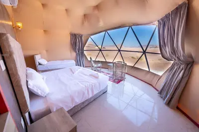a bedroom with a bed and a large window at Ahmad Wadi Rum Camp in Wadi Rum