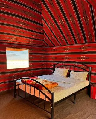 a bed in a room with a red wall at Wadi Rum Bedouin in Wadi Rum