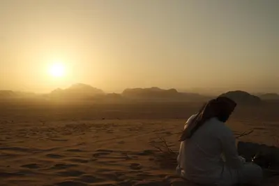 a woman sitting in the desert watching the sunset at Wadi Rum Bedouin in Wadi Rum