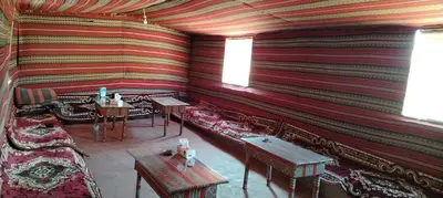 a room with a couch and tables and a striped wall at Nature rum camp in Wadi Rum