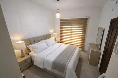 a bedroom with a large white bed and a window at Cozy Studio Gardens St Neighborhood in Amman