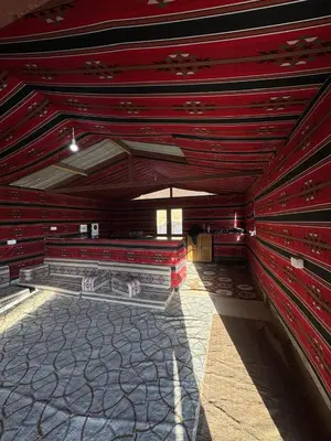 a room with red wooden walls and a floor at Bedouin Family Camp in Al Ḩayy