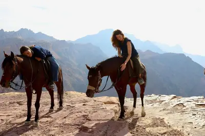 two people riding on horses on a mountain at Bedouin Family Camp in Al Ḩayy