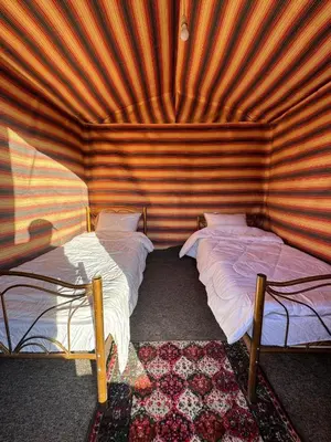 a room with two beds in a wooden wall at Bedouin Family Camp in Al Ḩayy