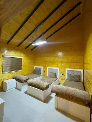 a room with three beds and a yellow wall at شاليه غصن in Ajloun