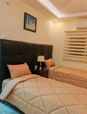 a bedroom with two beds and a table with a lamp at I cloud Petra hostel in Wadi Musa