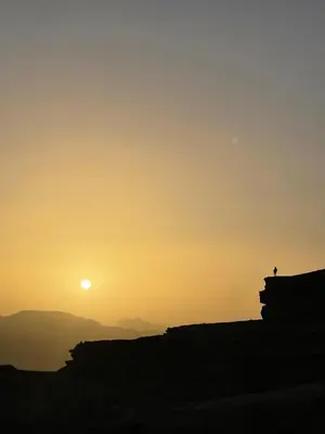 a person sitting on a bench watching the sunset at Wadi Rum Heritage Camp in Wadi Rum