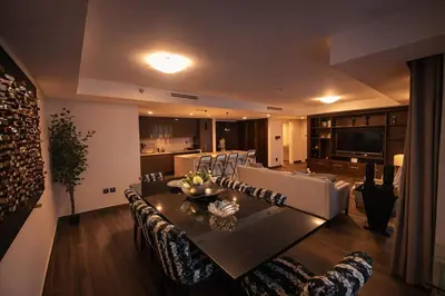 a living room with a dining table and a kitchen at Gampbell Gray Elite Abdali Apartment in Amman