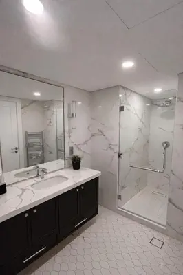 a bathroom with a shower and a sink and a mirror at Gampbell Gray Elite Abdali Apartment in Amman