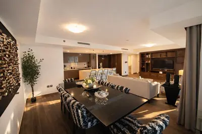 a dining room and living room with a table and chairs at Gampbell Gray Elite Abdali Apartment in Amman