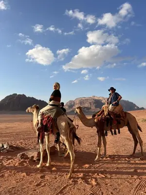 two people are riding on camels in the desert at Wadi Rum Tours and Camp in Wadi Rum