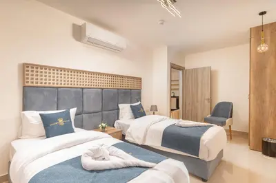a hotel room with two beds and a chair at Golden Pillar Hotel in Aqaba