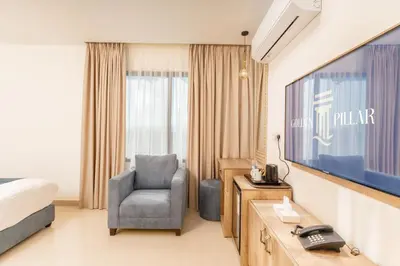 a hotel room with a bed and a chair and a television at Golden Pillar Hotel in Aqaba