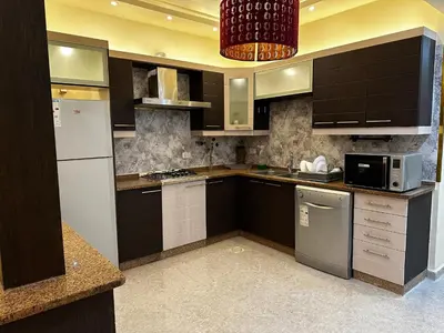 a kitchen with black cabinets and a white refrigerator at شقة بالرابية in Amman
