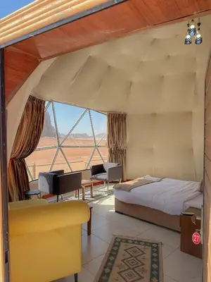 a bedroom with a bed and a large window at BUBBLES CAMp in Wadi Rum
