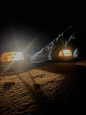 a couple of tents on a beach at night at Desert Stars Bubble Camp Wadi Rum in Wadi Rum