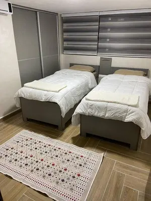 two beds in a room with a rug on the floor at Kirakoupdolis house & restaurant in Kerak
