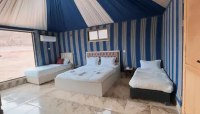 two beds in a room with blue and white stripes at Aseel camp rum in Wadi Rum