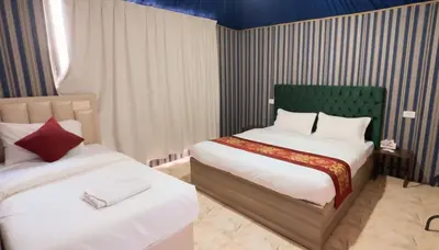 a bedroom with two beds and a green headboard at Aseel camp rum in Wadi Rum