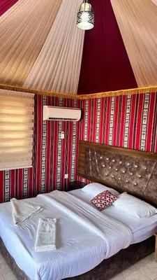 a bedroom with a large bed with a red wall at Wadi Rum Desert Memory in Wadi Rum