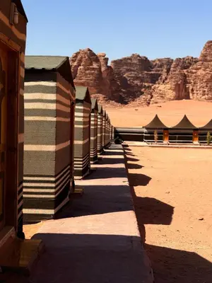 a row of buildings in the desert with mountains at Desert Moon Camp in Wadi Rum