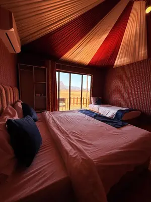 a bedroom with a large bed and a large window at Desert Moon Camp in Wadi Rum