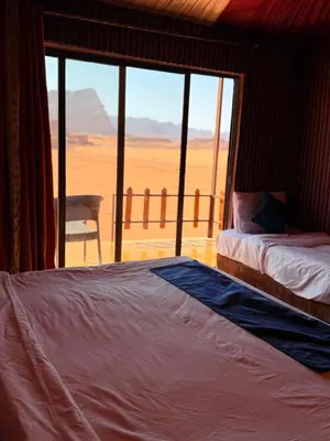 a bedroom with two beds and a view of the desert at Desert Moon Camp in Wadi Rum