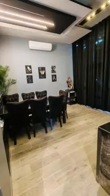 a room with a table and chairs and a woman in the background at LP chalet deadSea view in Sowayma