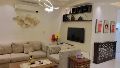a living room with a couch and a tv at Lavender Résidence 102 in Amman